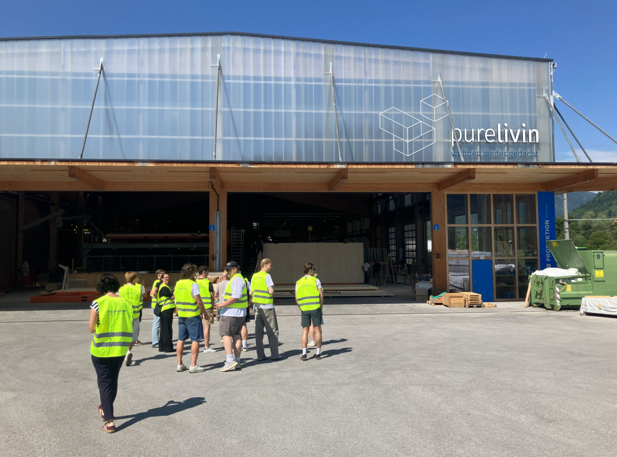 Gruppe in Warnwesten vor der PureLivin-Produktionshalle mit Holzvordach